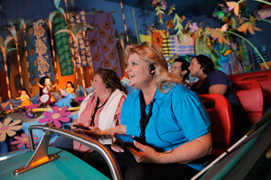 A female Guest enjoying It's a Small World ride with her family through an Assistive Listening device.