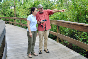 A man explaining how the Handheld captioning works to a woman