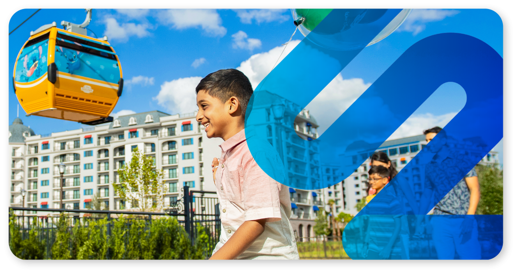 Photo of a young boy at Disney's Riveria Resort with a Skyliner gondola overhead. The SyncLink icon is overlayed on top of the image in blue.